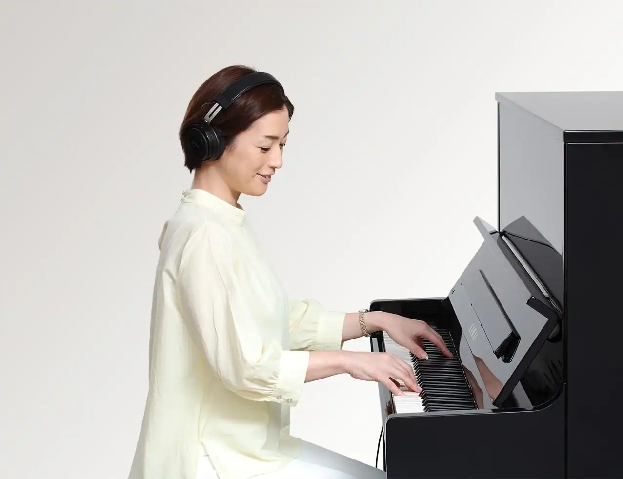 Sieviete spēlējoša klavieres ar austiņām, mūzikas instruments, K-15 ATX3L modelis.